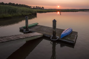 Two canoes on a dock along the water at sunrise.